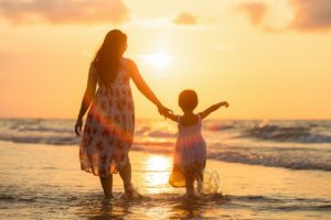 mãe e filha caminhando na praia