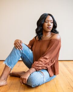 woman sitting on the floor wearing a brown shirt and jeans