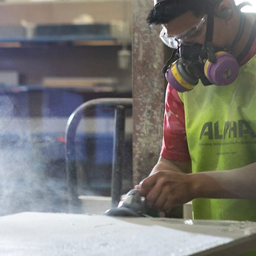Worker in a mask cutting dangerous artificial stone countertop